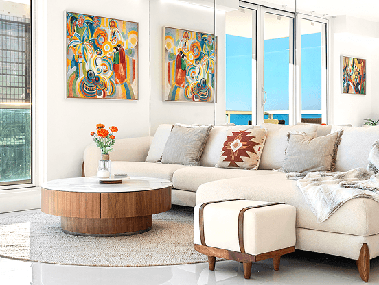 Modern living room with white furniture, colorful artwork, and large windows